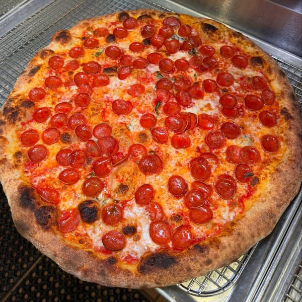 A freshly baked Brooklyn DOP pepperoni pizza with a crispy crust, melted cheese, and vibrant red pepperoni.