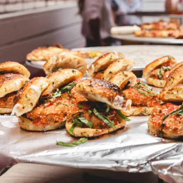 Mini meatball sliders with tomato sauce and basil on a foil-lined tray at Brooklyn DOP.
