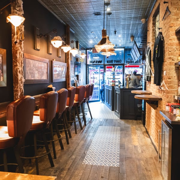 Interior of Brooklyn DOP pizza restaurant with bar seating, brick walls, and a view to the street.